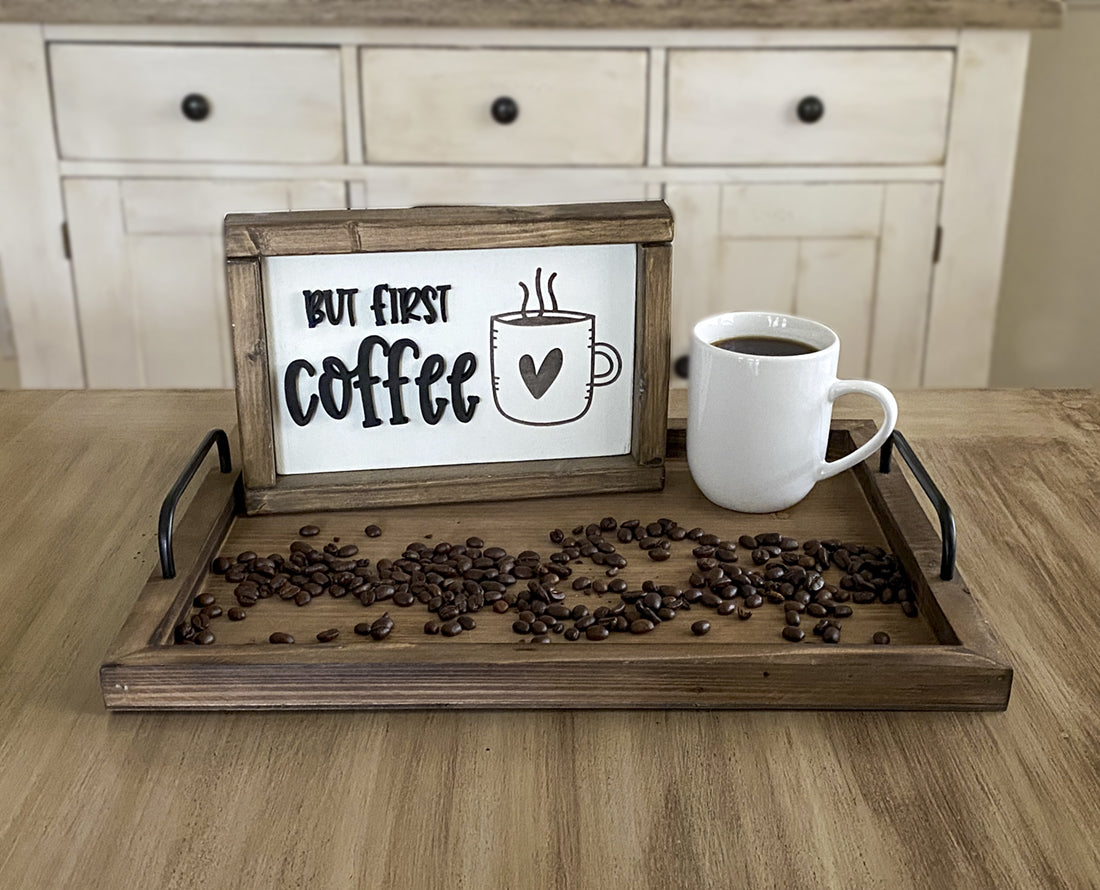 Cup of coffee on a tray with a wood sign that says but first coffee