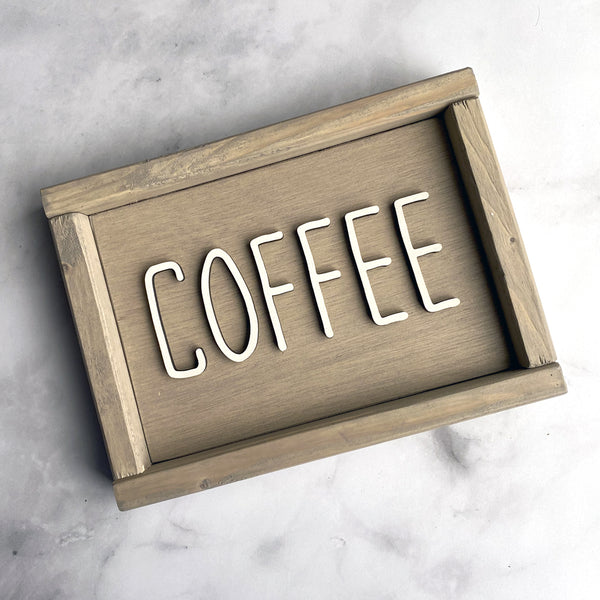 beige wood sign that says Coffee in white lettering on gray background