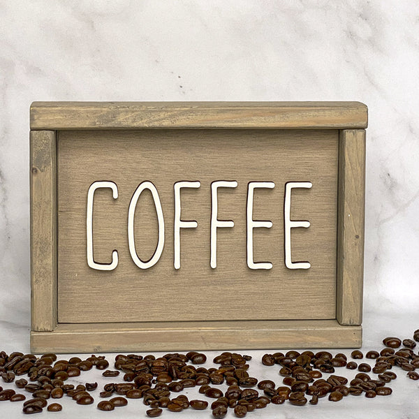 beige wood sign that says Coffee in white lettering with coffee beans around it