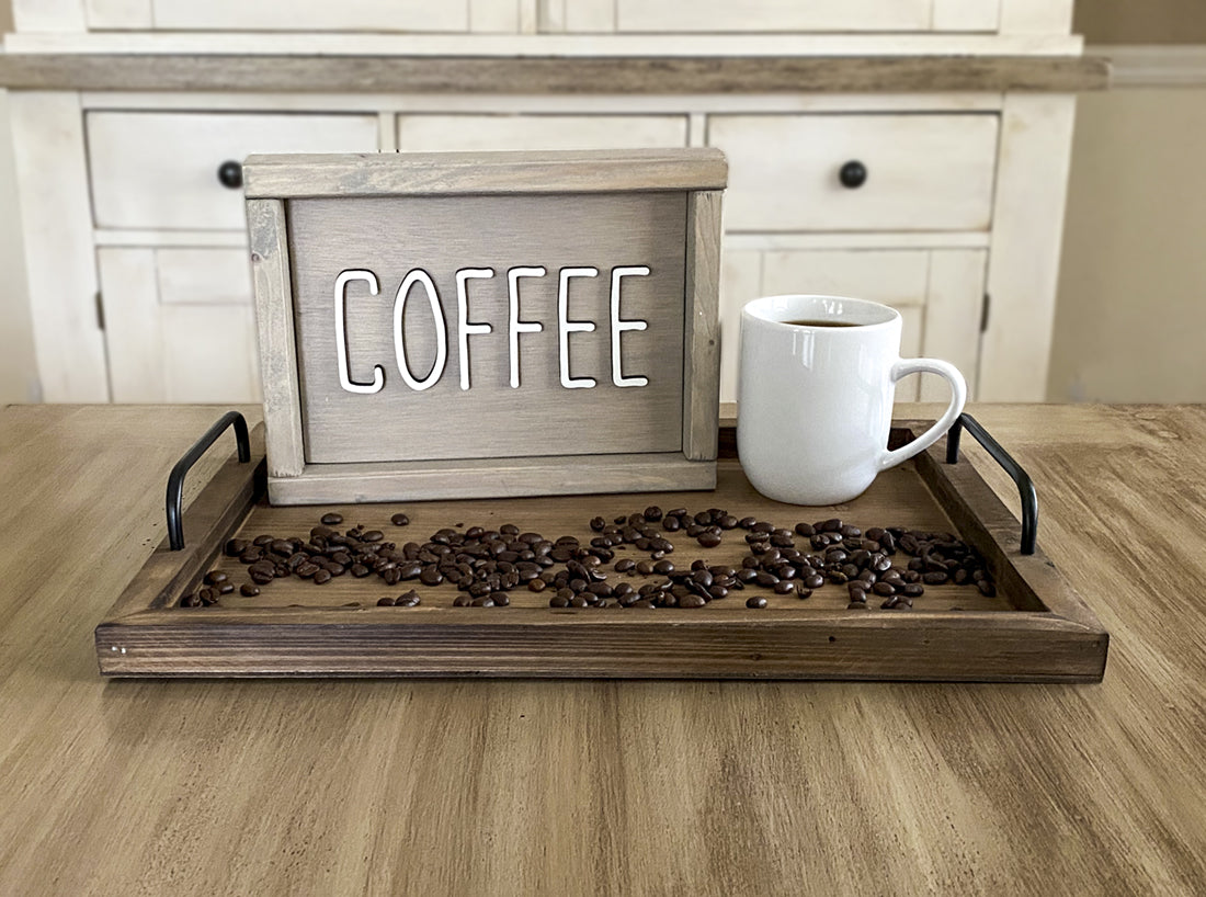 beige wood sign that says Coffee in white lettering on a tray with a cup of coffee and coffee beans