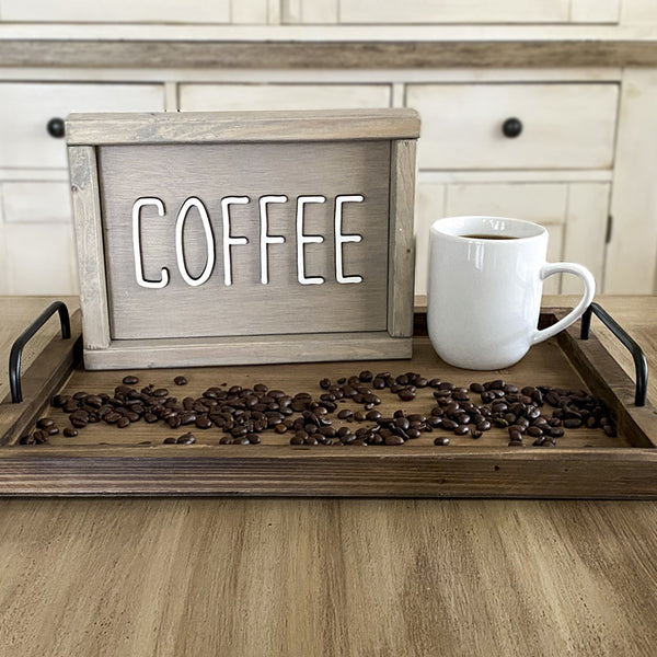 beige wood sign that says Coffee in white lettering on a tray with a cup of coffee and coffee beans