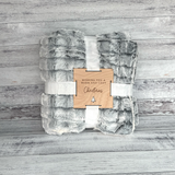 Plush blanket with a wooden tag on a wooden surface