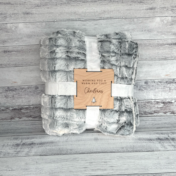 Plush blanket with a wooden tag on a wooden surface