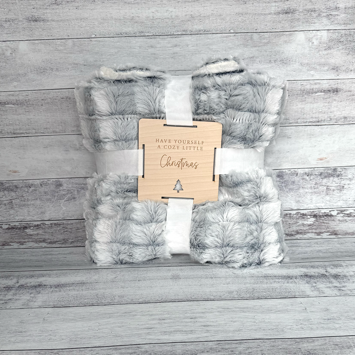 Soft blanket with a wooden tag on a wooden surface