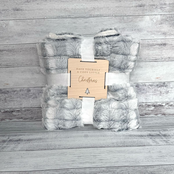 Soft blanket with a wooden tag on a wooden surface