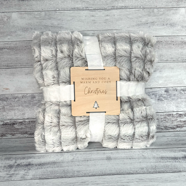 Brown and white blanket with a Christmas tag on a wooden surface