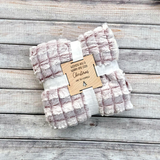 Folded blanket with a wooden tag on a wooden surface