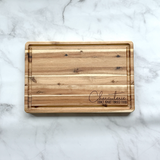 Wooden cutting board with engraved text on a marble surface