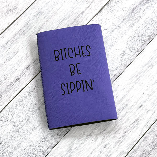 Purple notebook with 'Bitches Be Sippin'' text on a wooden surface