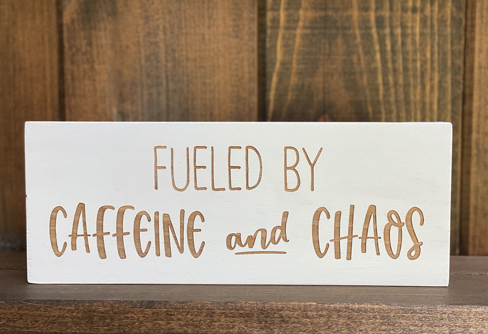 Closeup of fueled by Caffeine and Chaos wood sign