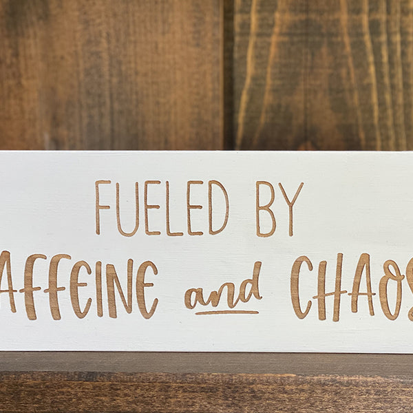 Closeup of fueled by Caffeine and Chaos wood sign