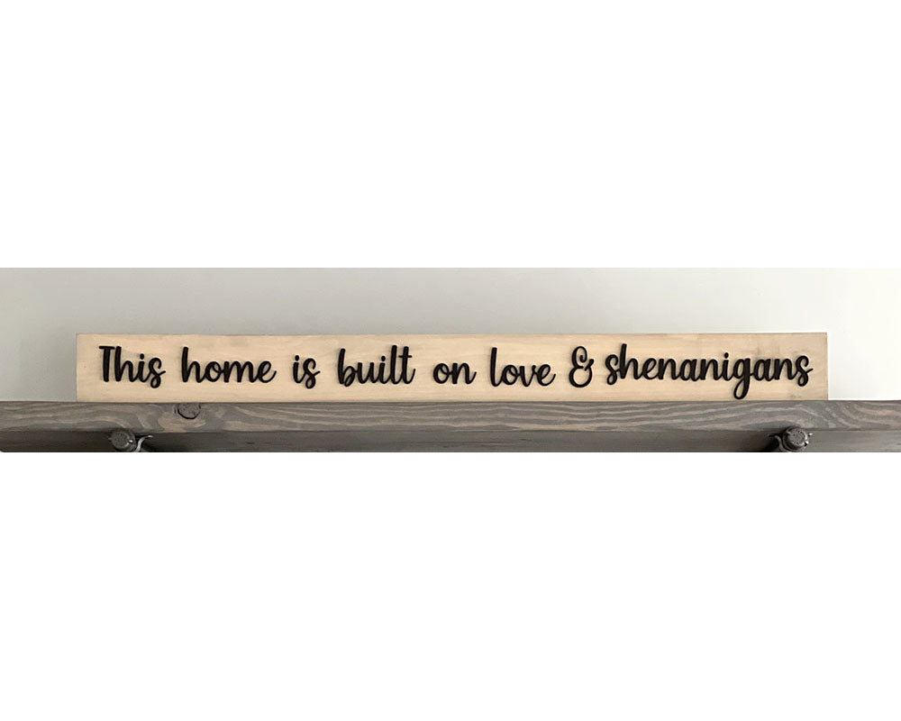 Closeup of This home is built on love & shenanigans wood sign