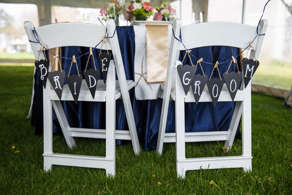 Chalkboard pennant flags were hung on the couple's chairs with navy raffia and mini clothespins. Signs by SKO Designs. Photography by Organic Photography.