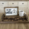 Cup of coffee on a tray with a wood sign that says but first coffee